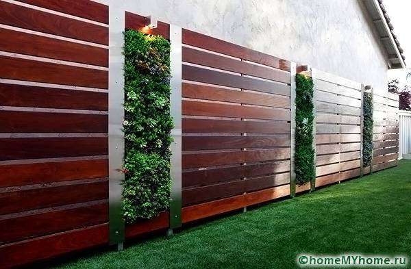 Саксиите с цветя, фиксирани върху опори, ще помогнат да превърнете оградата в цветно легло