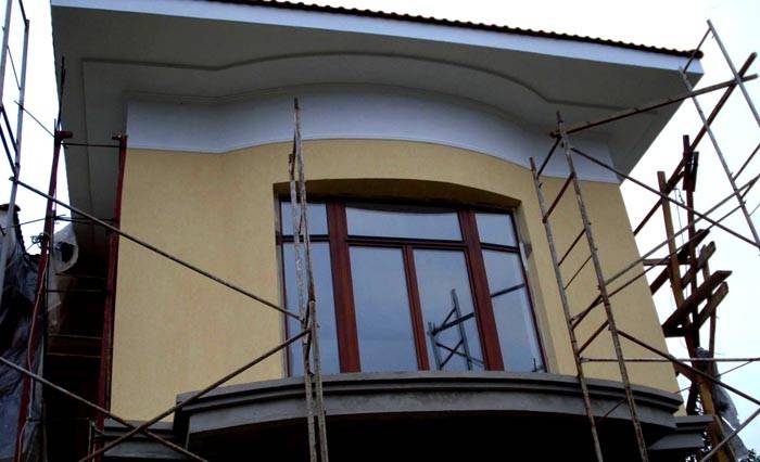 Deze foto van de gevelversiering met schorskever toont de noodzaak om steigers te gebruiken voor veilig werken op hoogte