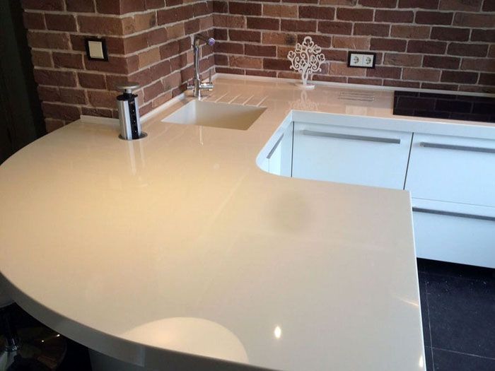 Dari batu buatan, anda boleh membuat meja kerja satu bahagian dengan bentuk yang kompleks dengan sinki terbina dalam