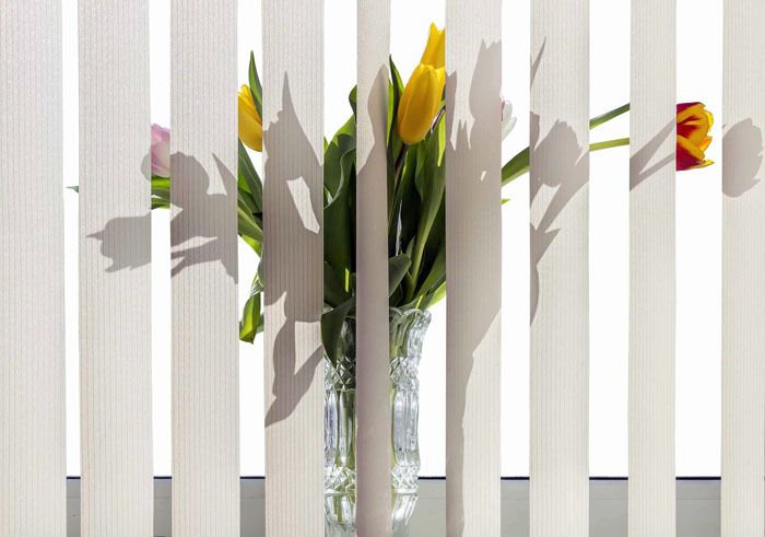 A logical way out is to mount the curtain on the wall in front of the window opening. So, the flowers will remain on the windowsill, and the frame will not suffer