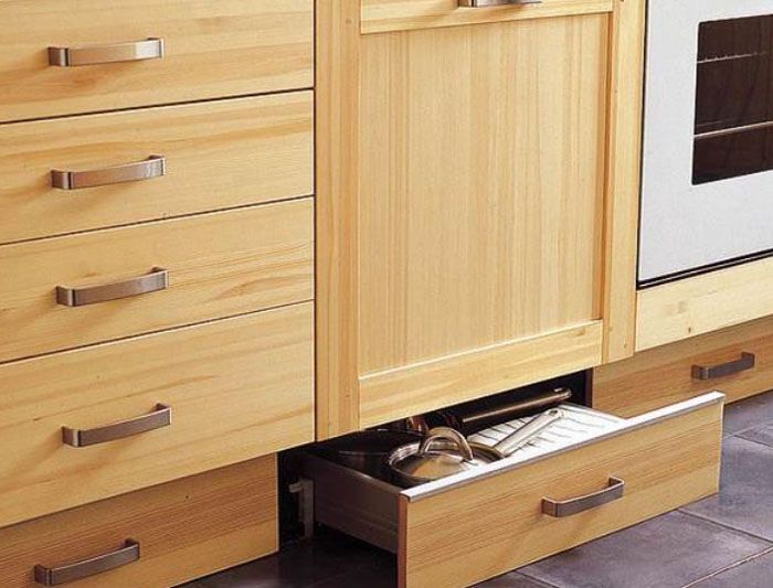Instead of free space with plugs, built-in drawers on rails are installed under the main cabinets