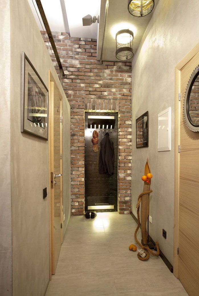 Una parete divisoria separa il corridoio dal resto della casa e basta l'illuminazione sotto forma di una piccola lampada originale con paralume in metallo. Per i corridoi stretti, non è necessaria un'abbondanza di luce