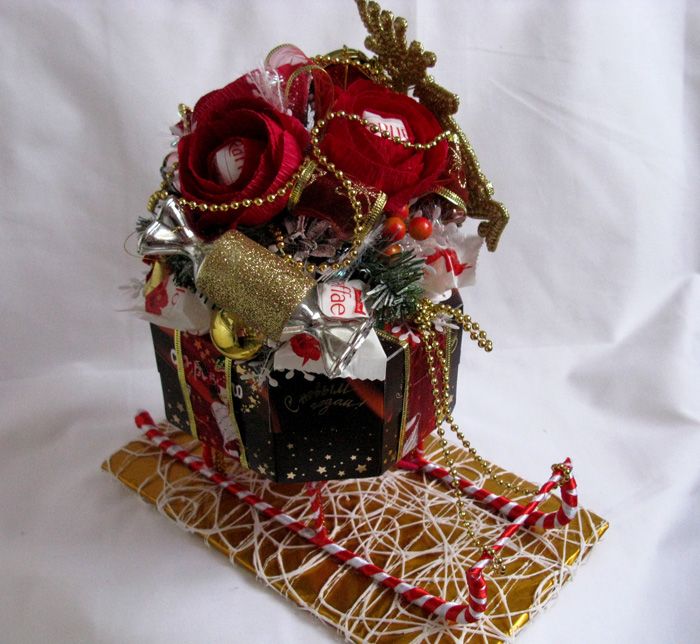 An easy-to-manufacture version of the sled: the chocolate base is decorated with gold foil, we install cane runners made of wire wrapped in red and white ribbons on it.We put goodies in the box and don't forget about the decor