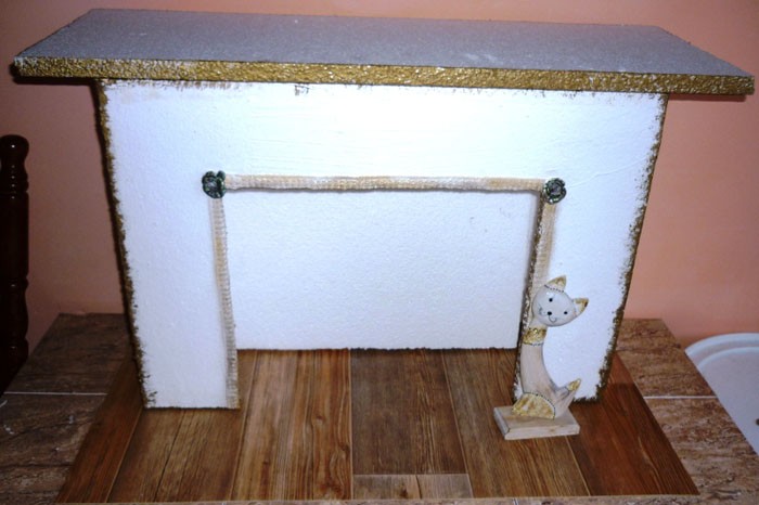 Chúng tôi dán tấm bìa lớn hơn lò sưởi. Để có hiệu ứng tốt nhất, phần cắt của hộp cứu hỏa và các bề mặt bên được phủ bằng lớp mạ vàng