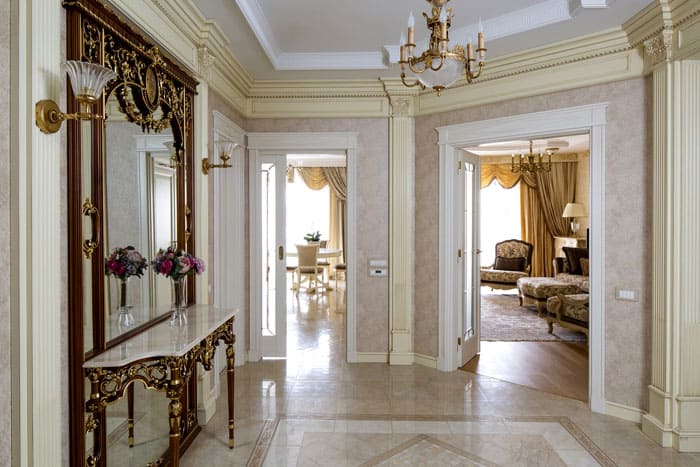 In the center of the hallway, there is an antique decorated mirror with the same royal console